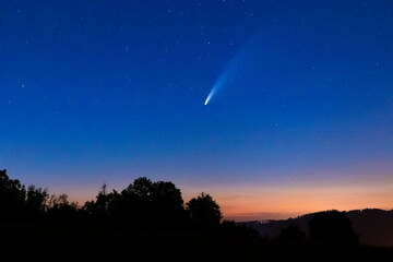 Comet Neowis moving shortly after sunset in a blue sky to the side captured over the mountainous...