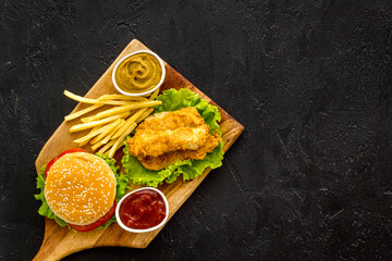 Fast food set. Delicious burger with french fries on wooden cutting board
