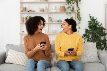 Obraz premium Online victory, amazing event, shocking news. Surprised cute millennial african american ladies with mobile phones