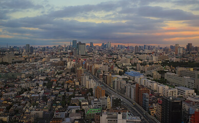 Fototapeta na wymiar Aerial early evening view of the Shibuya skyline as seen from southwestern Tokyo on a partly cloudy day