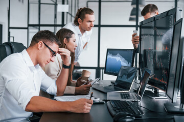 Naklejka premium Analysing information. Team of stockbrokers works in modern office with many display screens