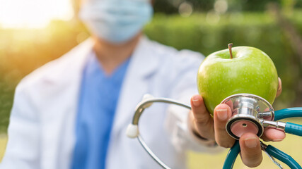 World health day, an apple a day keeps the doctor away concept for health benefit by eating high nutritious clean food and healthy nutritional diet with doctor handling green apple giving to patient