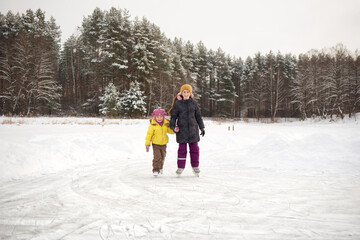 active rest on nature. children skates on natural ice rink - lake. winter fun with children outdoors