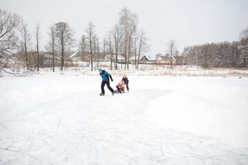 active rest on nature. family skates on natural ice rink - lake in village. winter fun with children outdoors
