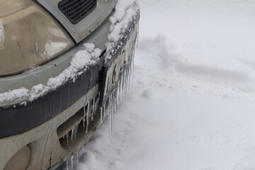 Icy car bumper, icicles on the car in winter.
