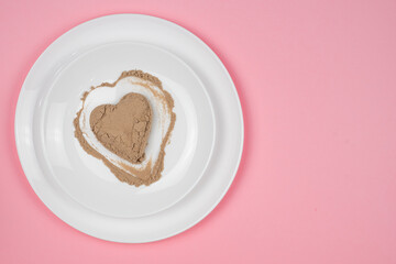 Collagen powder or protein is scattered randomly over the surface of the plate. Heart shaped empty space. Supplement to a healthy diet. The 14th of February