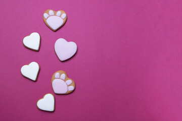 Valentine cookies in form of cat paws on red colored paper background with copyspace