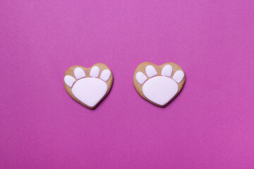 close up of valentine cookies in form of cat paws on purple colored paper background