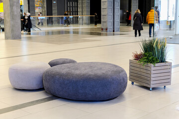Sitting area in lobby, large shopping center - round ottoman fabric and artificial plants as...