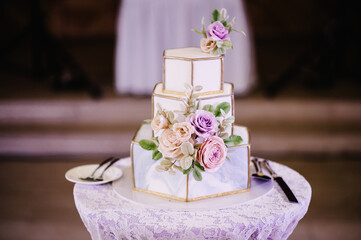 A classic tiered white and grey cake with flowers decoration and geometric pattern. A wedding cake.