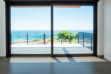 Empty room with large panoramic windows overlooking the sea. Room after major renovation.