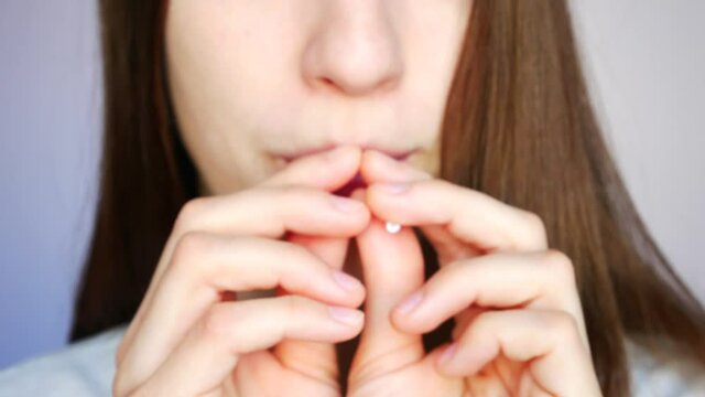 A lower part of a face of a girl holding red and green lollipops and sucking them close-up