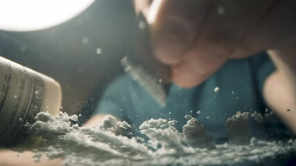 Cocaine addict cutting lines of white powder with a razor blade, US dollar bill. - Powered by Adobe