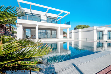 The modern facade of a luxury villa with a large swimming pool. Luxury MODERN property.