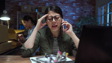SME internet shop office concept. Depressed young asian woman serious talking with mobile phone and...