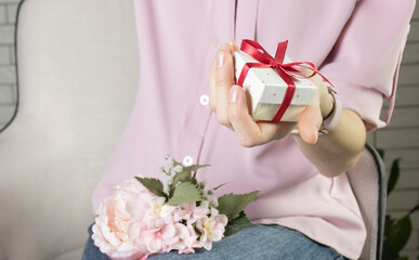 Close-Up Of Female Hands Holding A Present. The Trendy Pink Desk.