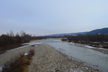 Late autumn landscape. Cold gray water, ducks, dry grass, first snow in the foreground and silhouettes of trees in the background. Autumn mood.