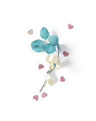 The eucalyptus branch is wrapped in a yellow satin ribbon and is on a white background. Shiny figures of hearts are scattered nearby. Valentine's Day minimalist layout. Flat lay. Top view.