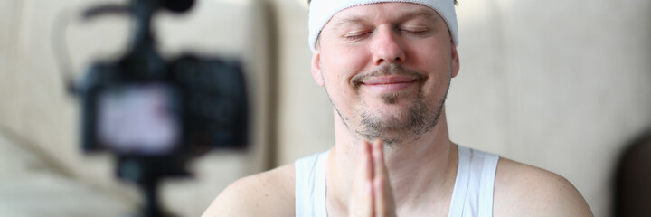 Handsome male person keeping smile on his face while shooting tutorials on his camera