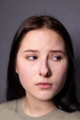 Fototapeta premium portrait of charming sad brunette woman in marsh color t-shirt on grey wall background. actress acting, emotion