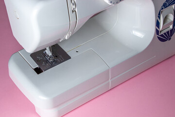 White sewing machine on a pink background. Electric sewing machine. Handmade tool. Sewing business.