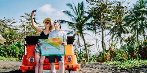 Carefree couple taking selfie standing with map
