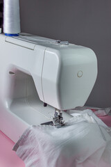 White sewing machine on a pink background. Electric sewing machine. white fabric on the sewing machine. Handmade tool. Sewing business.
