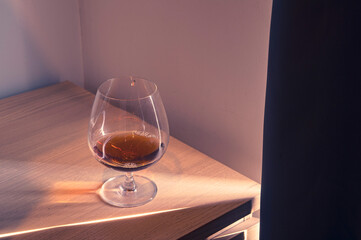 Glass and alcohol on wooden desk with dramatic light