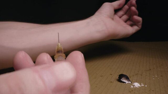 Heroin addict junkie injecting Syringe needle heroin into arm. Opiate addiction.