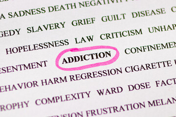 Highlighting the word addiction with a pink marker, view through a magnifying glass. Bad habits of a person, for social advertising