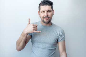 Attractive happy hipster man gesturing with fingers call me