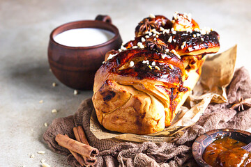 Apricot jam twisted loaf bread or babka with nuts and spices on concrete background with a cup of milk. Homemade yeast bun babka.