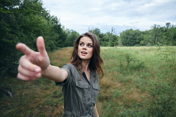 Woman on nature Green jumpsuit with outstretched hand shows a finger