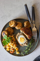 Homemade scotch eggs on a plate served with bulgur pilaf, grilled mushroom and aromatic herbs. Meat cutlet with boiled egg. Traditional English cuisine. Top view.