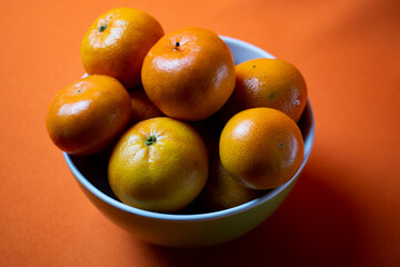 clementines in a bowl with orange background