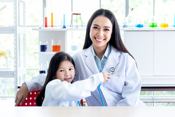 Portrait images of Asian woman teacher And a 6 year old girl student, wearing a white doctor...