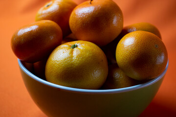 clementines in a bowl with orange background
