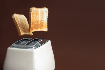 Slices of toast jumping out of the toaster on brown background