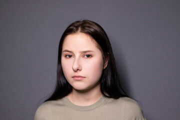 portrait of charming sad brunette woman in marsh color t-shirt on grey wall background. actress...