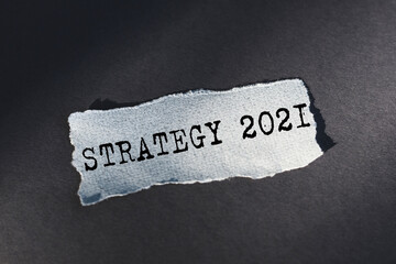 STRATEGY 2021 text on torn paper on dark desk in sunlight.