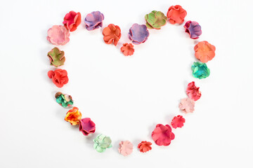 Beautiful paper flowers, folded in one big heart on a white background, as festive feelings on Valentine's Day, love. View from above. Copyspace. Close up image of beautiful flowers wall background