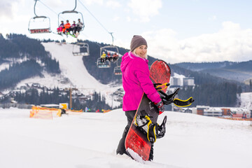 Young woman holding snowboard at winter resort