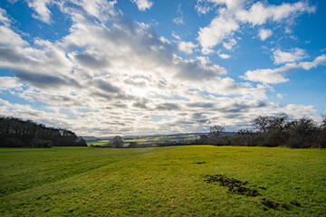 Obraz premium green field and beautiful mountain panorama at billiger berg near eiffel in the sun at euskirchen, germany