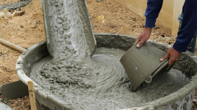 Close up Mixer truck pours liquid concrete into the concrete pump at the construction site