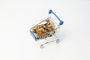 Shopping cart full of coins.Shopping concept with shopping supermarket trolley on isolated white background.E-commerce, business marketing with copy space.Save and spend money.