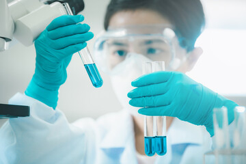Doctor or scientist in laboratory holding liquid vaccines in medical research lab or science...