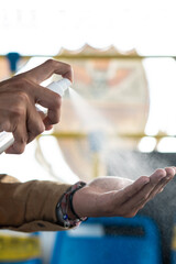 Latino man sanitizing his hands with alcohol spray to go to college