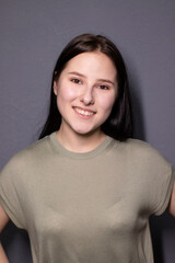 portrait of charming happy brunette woman in marsh color t-shirt on grey wall background. actress acting, emotion.