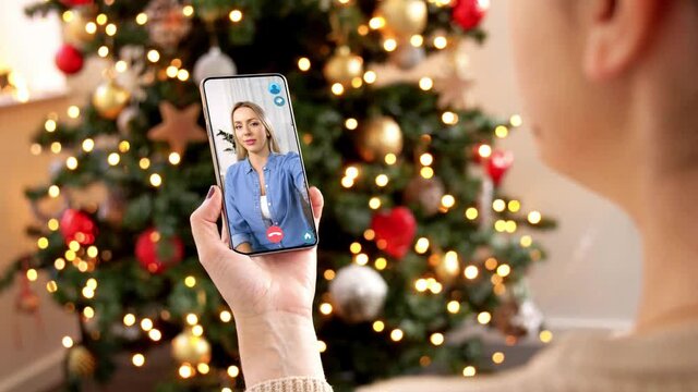 christmas, technology and holidays concept - close up of woman with smartphone having video with female friend call at home