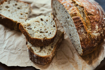 Homemade bread with cereals lies on rough craft paper. Delicious and fresh pastry made with your...